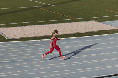 Active sportswoman running on track in stadium