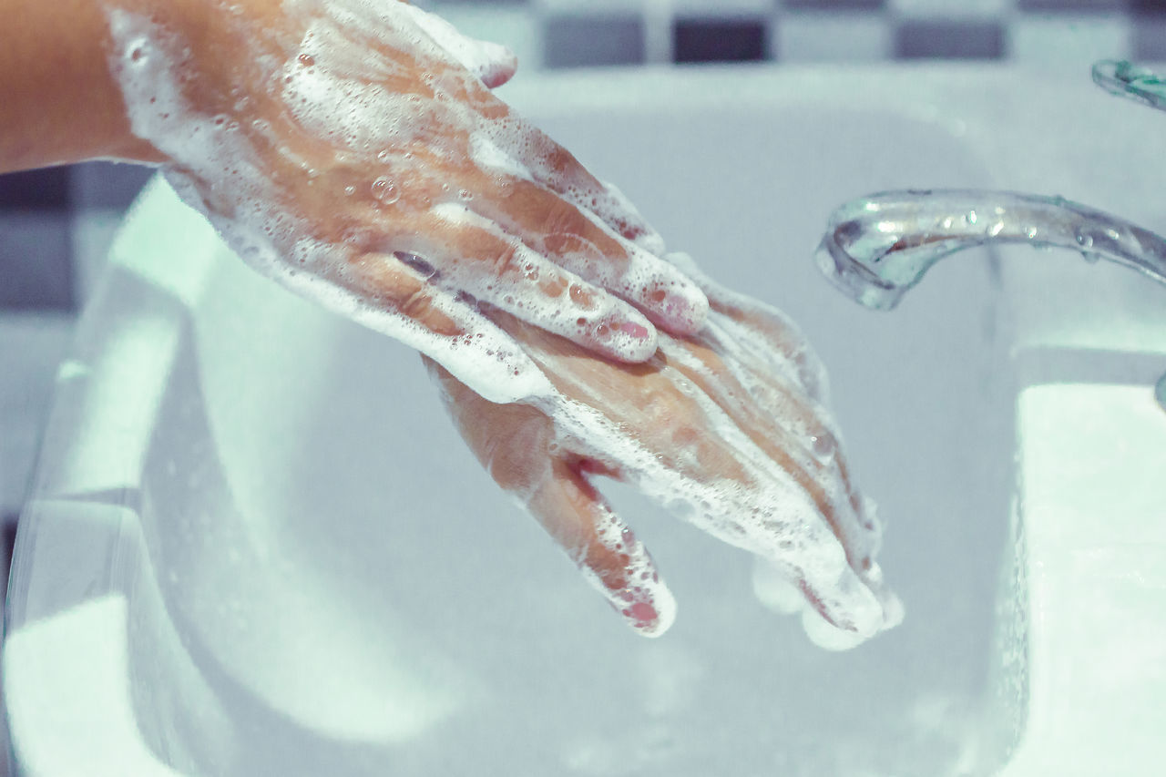 CLOSE-UP OF HAND HOLDING FISH IN SEA