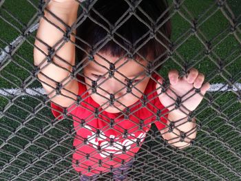 High angle view of boy lying on playing field seen through net