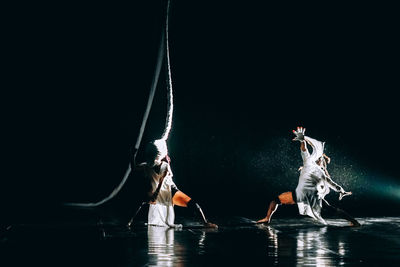 People dancing on water against black background