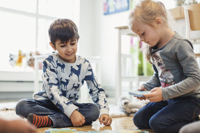 Happy children playing with jigsaw pieces at preschool