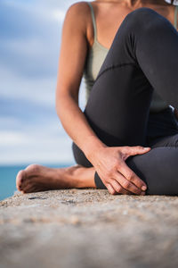 Low section of woman sitting on beach
