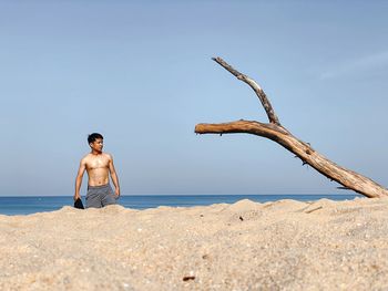 Young man on beach against clear sky