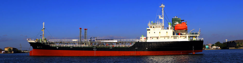 Red ship on sea against clear blue sky