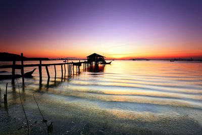 Silhouette pier over sea against clear sky at sunset