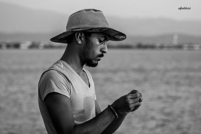 Man wearing hat standing by sea