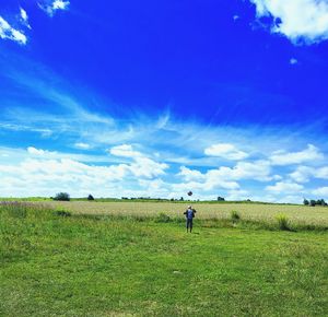 Rear view of man on field against sky