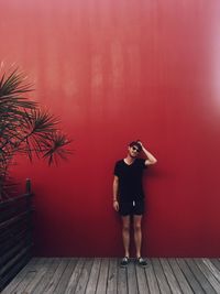 Woman standing against red wall