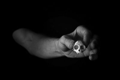 Close-up of hand holding leaf against black background
