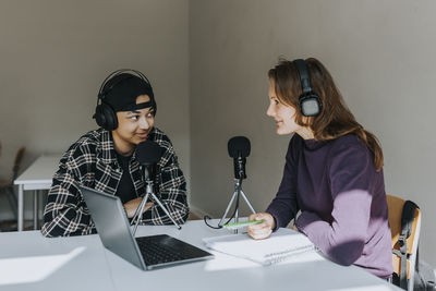 Young male and female student talking during podcast in classroom