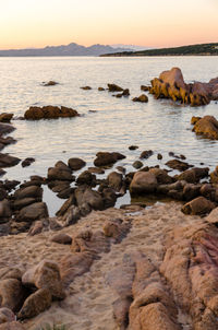 Rocks on beach against sky during sunset