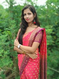 Portrait of beautiful young woman standing against plants