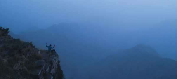 A man sits on the ledge of a cliff in al bahah, saudi arabia