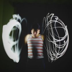 Man standing with light paintings against black background