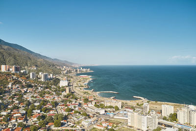 High angle view of townscape by sea against clear blue sky