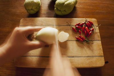 High angle view of hand holding bread on cutting board