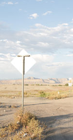 Street light on field by road against sky