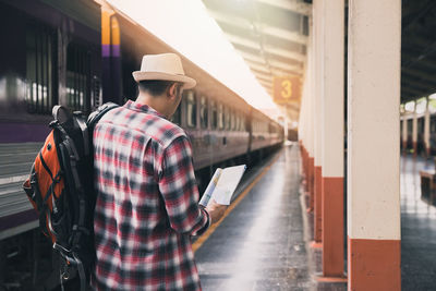 Rear view of man standing at railroad station