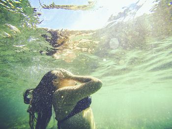 Close-up of sunlight falling on woman swimming underwater in pool