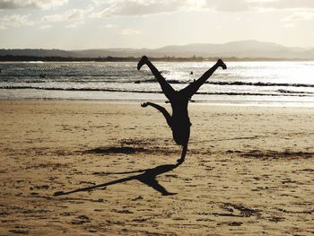 Silhouette man on beach against sky