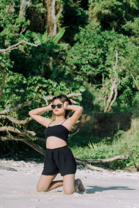 Portrait of young woman standing against trees