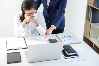 Midsection of businesswoman showing paper to woman in office