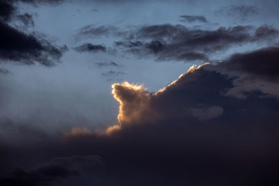 Low angle view of sunlight streaming through clouds
