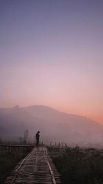 Rear view of men on road against sky during sunset