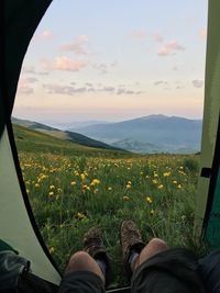 Low section of man standing on field against sky