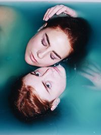 Portrait of young woman lying down in swimming pool