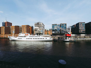 Boats moored at harbor against buildings in city