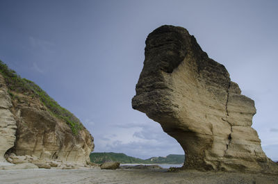 Low angle view of rock formation on beach against sky