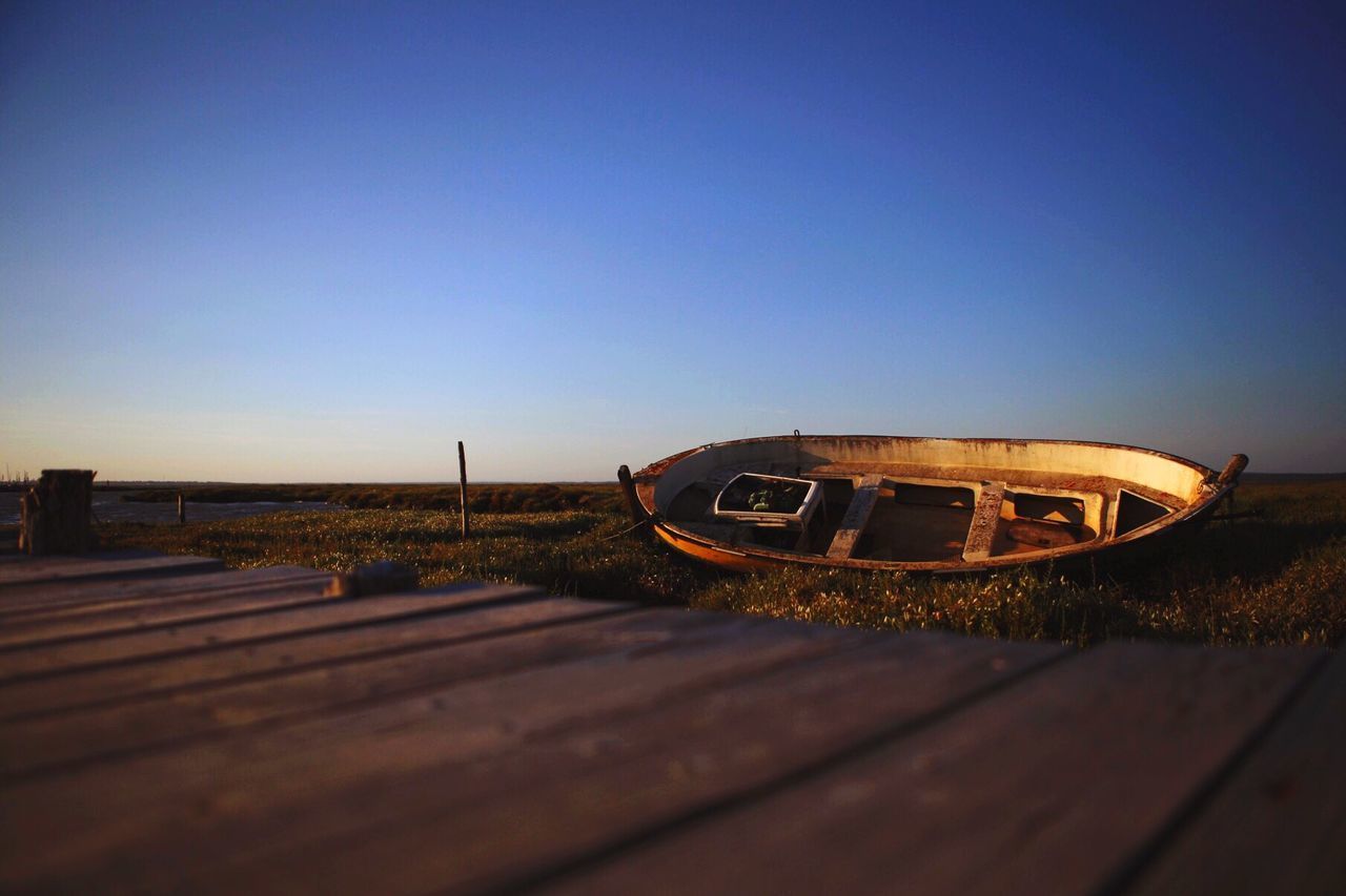 ABANDONED BOAT ON SHORE AGAINST CLEAR SKY