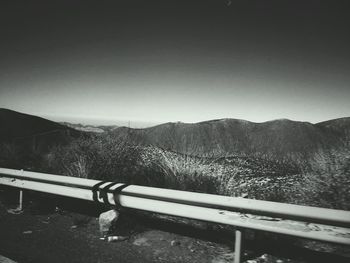 Snow covered railing by mountain against sky