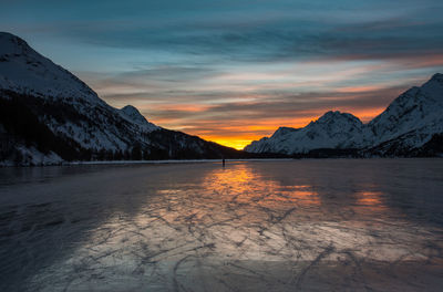 Scenic view of lake and mountains against sky during sunset