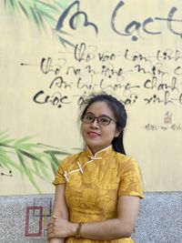 Portrait of smiling woman standing against wall