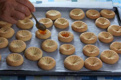 Hand with table spoon putting orange jam on cookies ready to eat