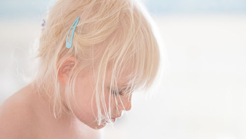 Cropped image of girl with short blond hair against sky