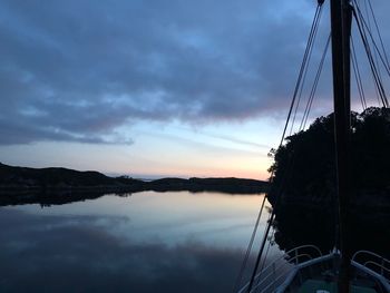 Silhouette of sailboat in lake against sky during sunset