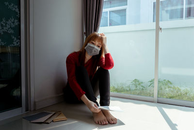 Woman sitting on window at home