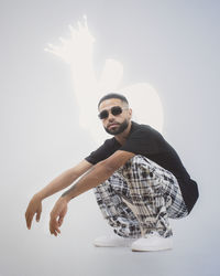 Portrait of young man wearing sunglasses against wall