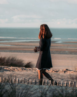 Woman standing at beach against sky