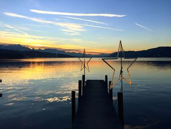 Pier over lake against sky during sunset