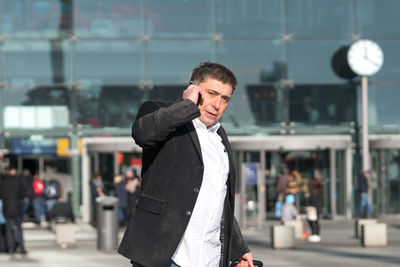 Businessman talking on phone while standing on city street