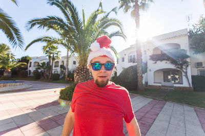 Portrait of man wearing sunglasses standing against trees