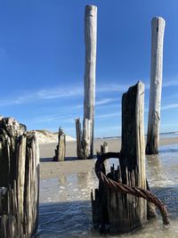 Wooden posts on beach against sky