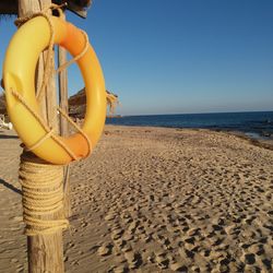 Deck chairs on beach against clear sky