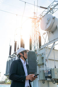 Low angle view of man using mobile phone against sky