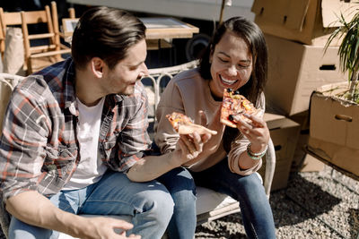 Cheerful couple eating pizza while relocating to new home