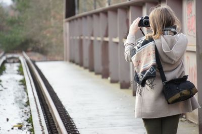 Rear view of mature woman taking selfie while standing on footpath